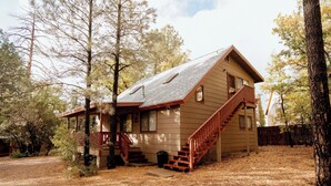 A two-story house with a steeply pitched roof, a front porch, and a staircase leading to the second floor. - Northwoods (#12) Cabin in the Pines (Pinetop-Lakeside)