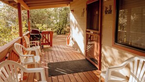 A covered porch with wooden flooring, white plastic chairs, and a grill. - Northwoods (#12) Cabin in the Pines (Pinetop-Lakeside)