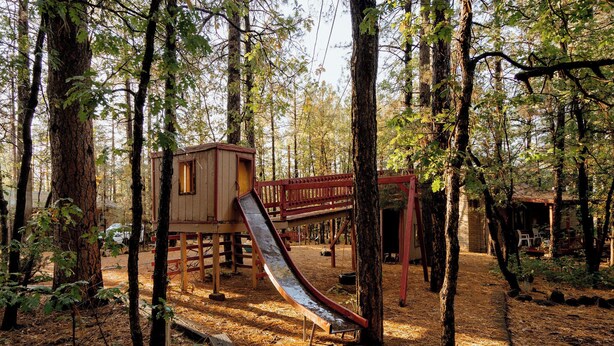 A playground with a slide and a wooden playhouse in a wooded area. - Northwoods #1 Cabin in the Pines (Pinetop-Lakeside)