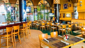 Un restaurante espacioso con techos altos, ventanas amplias y diferentes opciones de asientos, incluyendo mesas y sillas.