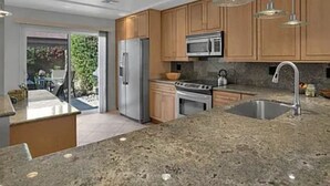 A modern kitchen with granite countertops, stainless steel appliances, and wooden cabinets. - Your Palm Desert Vacation Getaway at the Palm Valley Country Club is calling! (Palm Desert)