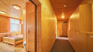 Un interior de madera con una cama, una mesa y una ventana con cortinas.