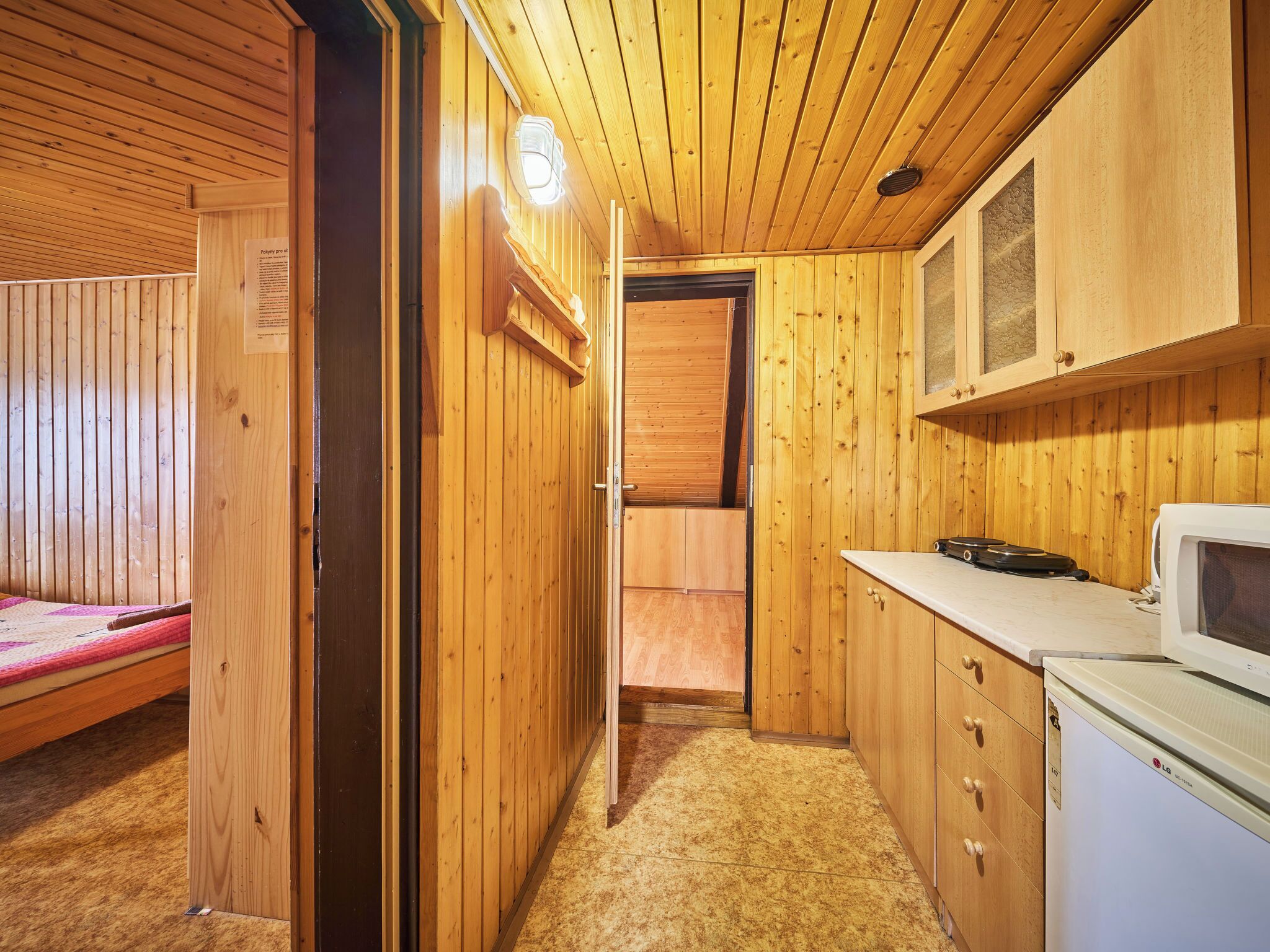 Une cuisine compacte avec des murs en bois, un four à micro-ondes et un petit réfrigérateur.