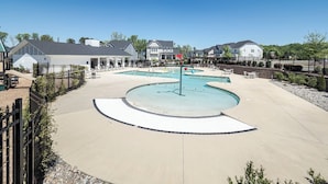 Ett bostadsområde med en swimmingpool, solstolar och hus.