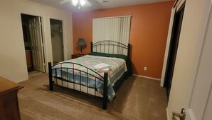 Une chambre à coucher avec un lit, une table de chevet, une lampe et une armoire.