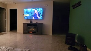 Un salon avec un téléviseur fixé au mur, une cheminée et un mur végétal.