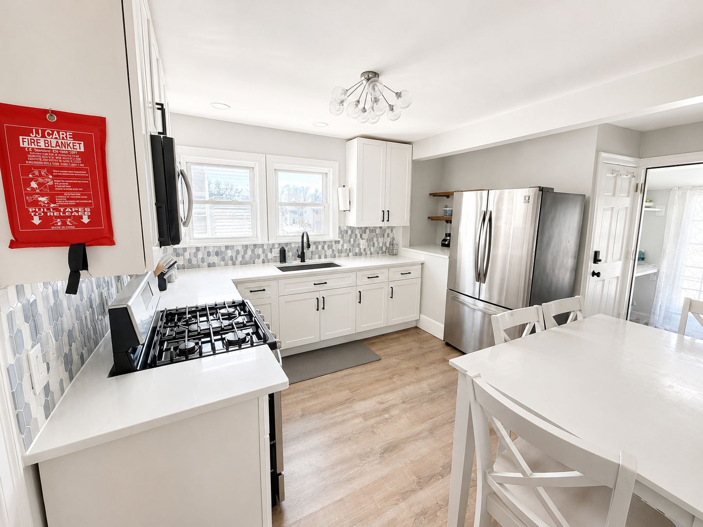 Una cocina moderna con armarios blancos, un refrigerador de acero inoxidable y una estufa a gas.