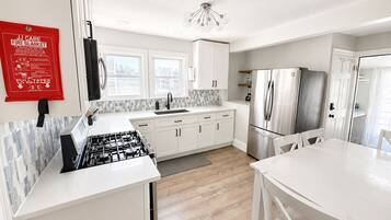 Una cocina moderna con armarios blancos, un refrigerador de acero inoxidable y una estufa a gas.