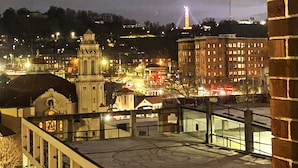 A nighttime cityscape with illuminated buildings, a prominent tower, and a bridge.