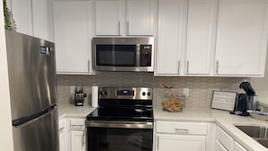 A modern kitchen with stainless steel appliances, white cabinetry, and a hexagonal tile backsplash.