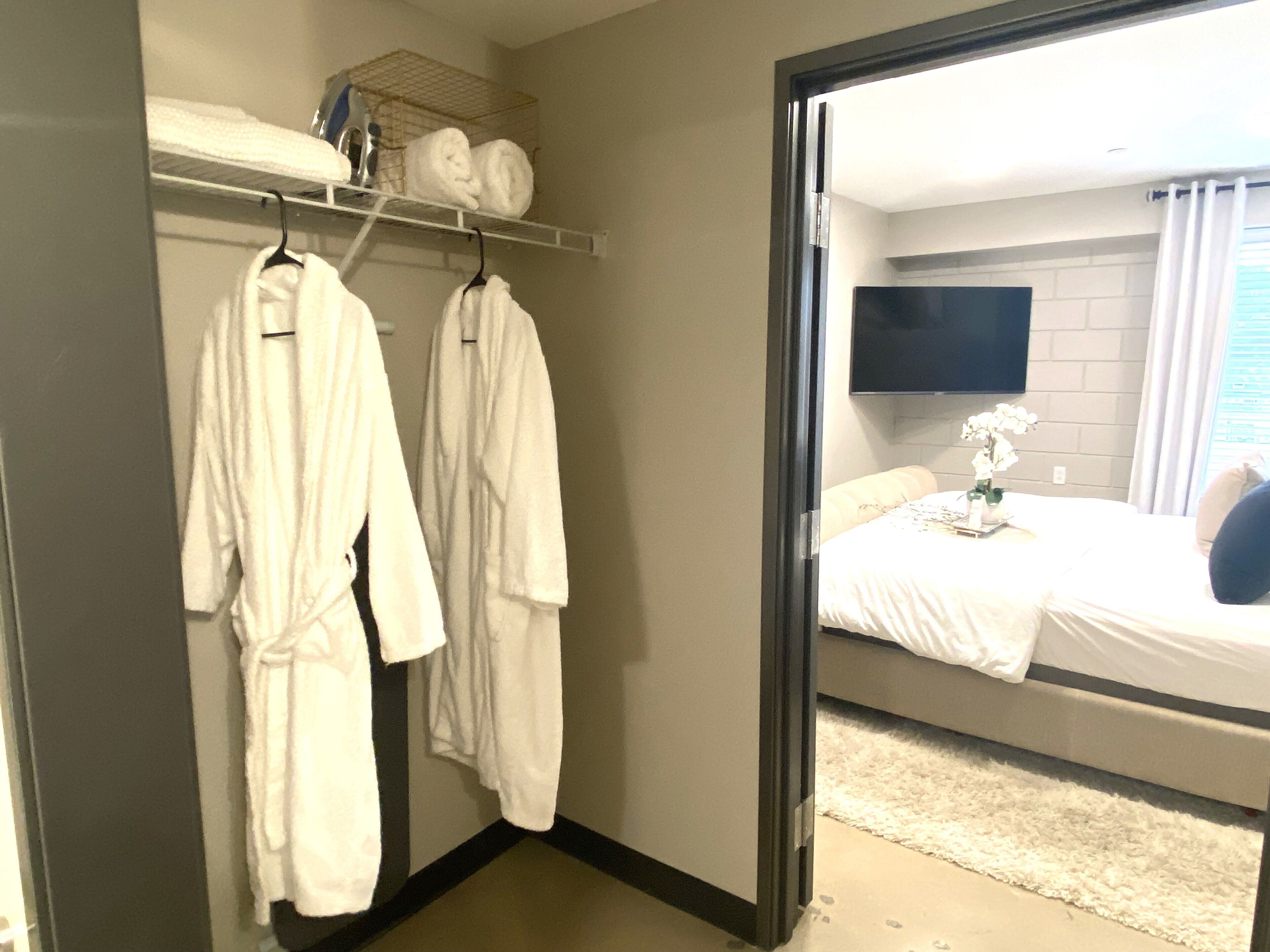 Una habitación de hotel con una cama, un televisor en la pared y un perchero con toallas.