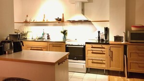 A modern kitchen with wooden cabinets, a central island, and a microwave. - Charming 8 person 4-bedroom villa  in wonderful City center Båstad in Skåne län (Skåne län)