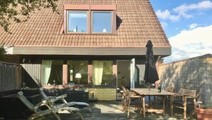 A house with a tiled roof, a balcony with lounge chairs, a wooden table with chairs, and a potted plant. - Charming 8 person 4-bedroom villa  in wonderful City center Båstad in Skåne län (Skåne län)