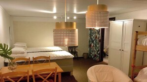 A bedroom with a bed, a wooden table with chairs, a white armchair, and a wardrobe. - Charming 8 person 4-bedroom villa  in wonderful City center Båstad in Skåne län (Skåne län)