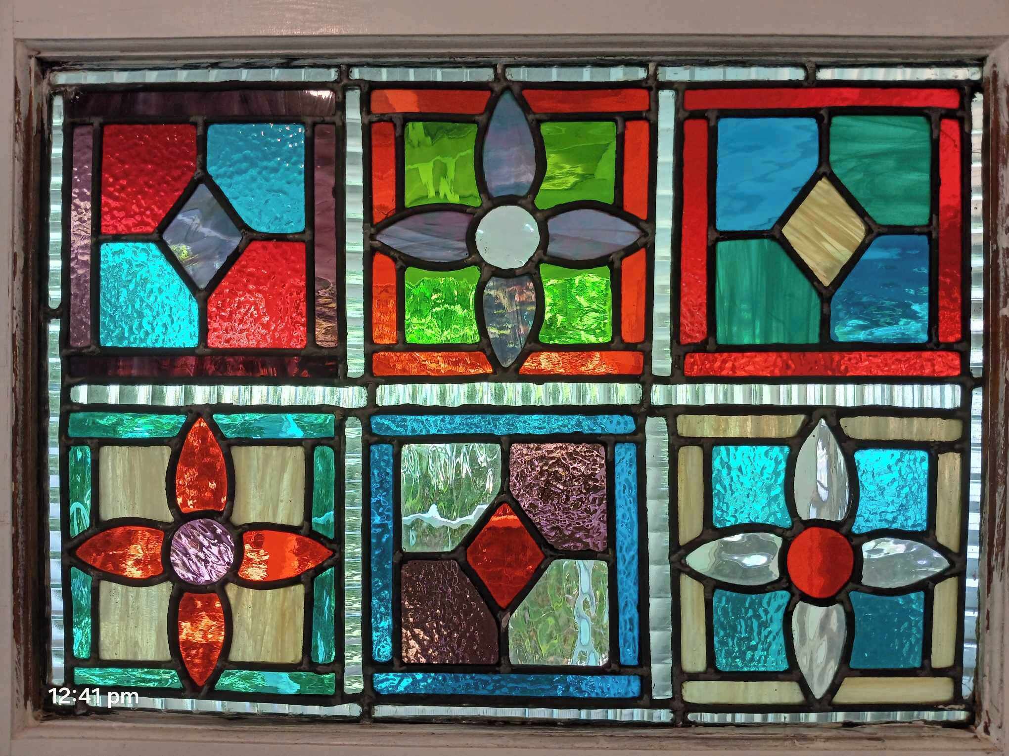 A stained glass window with geometric patterns and floral designs.