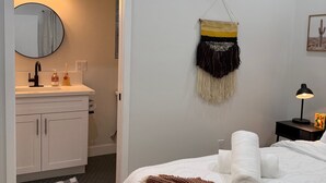 Makuuhuoneessa on sänky, yöpöytä, lamppu ja seinälle ripustettu seinävaate. Kylpyhuoneessa on pesuallas ja peili.
