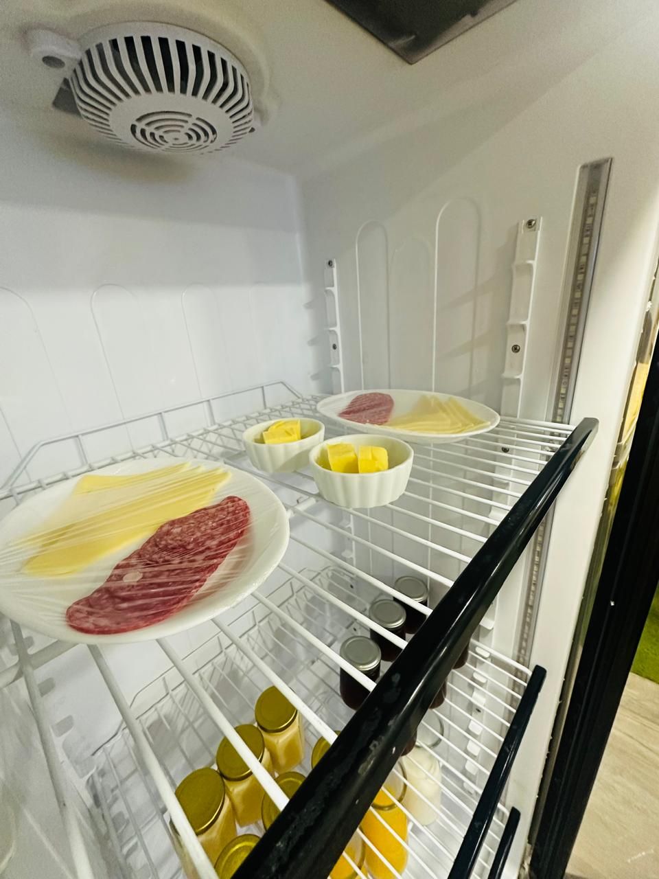 Un refrigerador con estantes que contienen alimentos y recipientes.