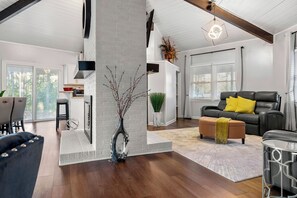 En moderne stue med pejs, spiseplads og en siddeområde med sofa og skammel.