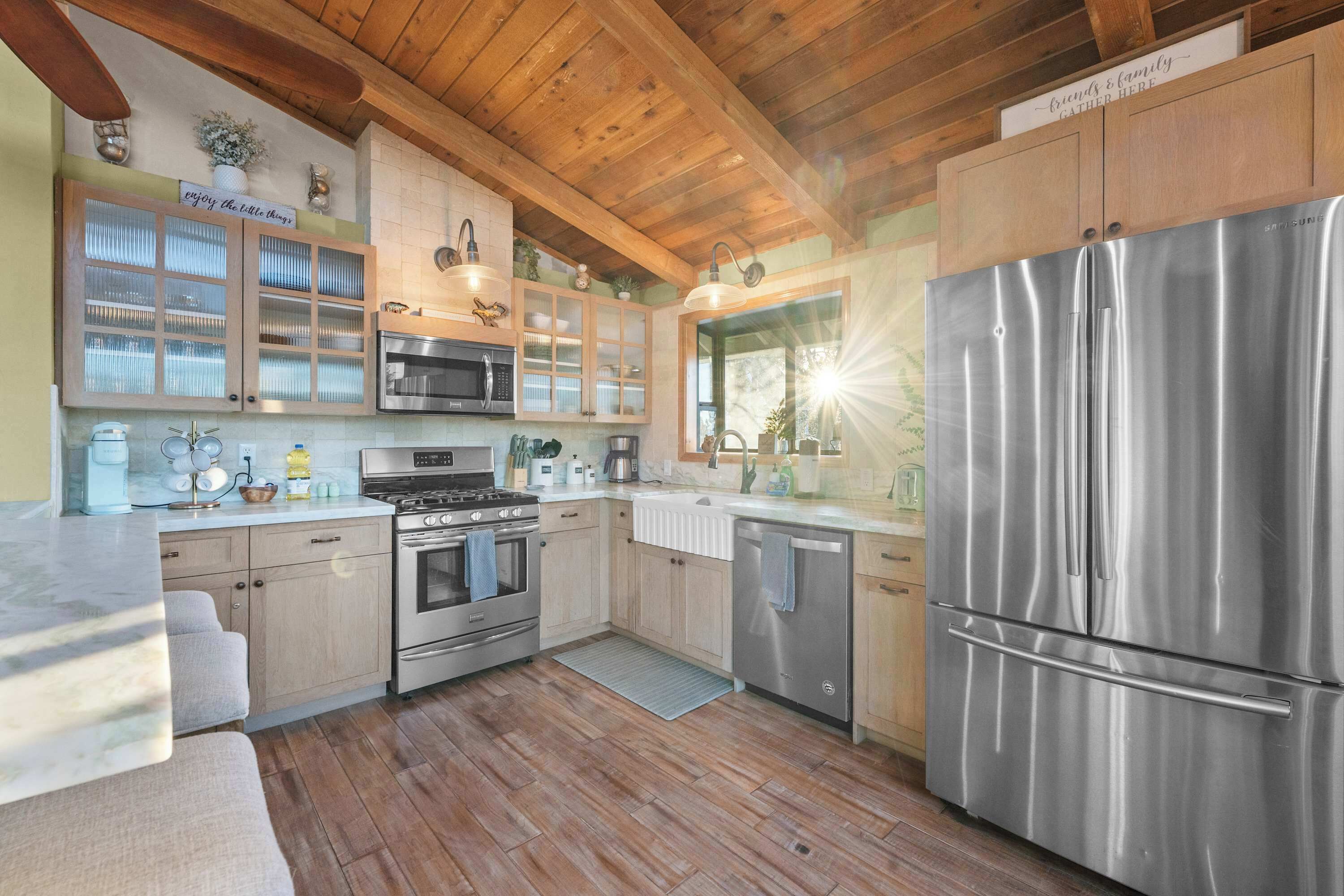 Une cuisine moderne avec des meubles en bois, des appareils électroménagers en acier inoxydable et un grand réfrigérateur.