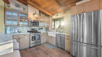 Une cuisine moderne avec des meubles en bois, des appareils électroménagers en acier inoxydable et un grand réfrigérateur.