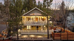 A two-story house with a balcony, a fireplace, and a well-lit porch area. - Eagles Nest•Walk to Village (Big Bear Lake)