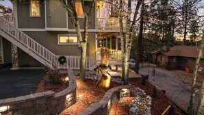 A two-story house with a balcony, a wooden staircase, and a bird sculpture in the yard. - Eagles Nest•Walk to Village (Big Bear Lake)