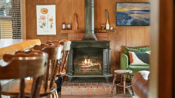 Une pièce chaleureuse avec une cheminée, des meubles en bois et un tableau accroché au mur.