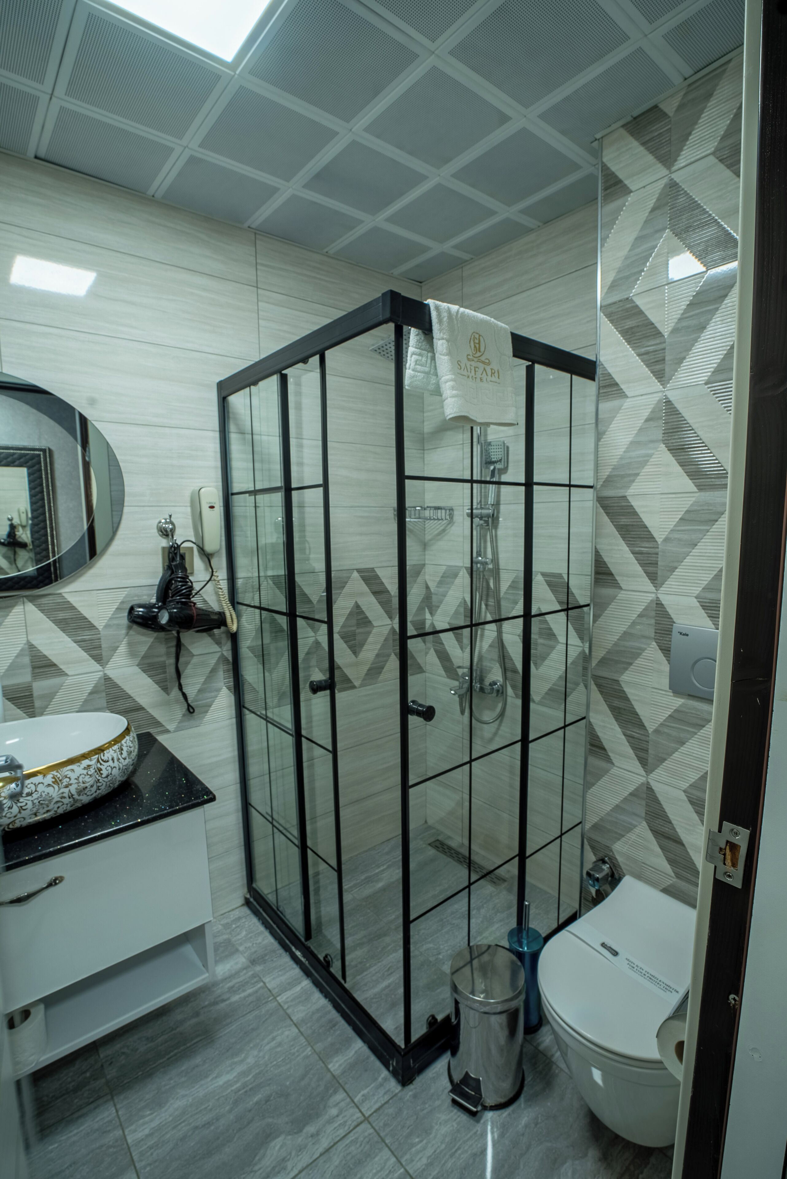 A modern bathroom with a glass-enclosed shower, a white sink with a decorative bowl, and a toilet.
