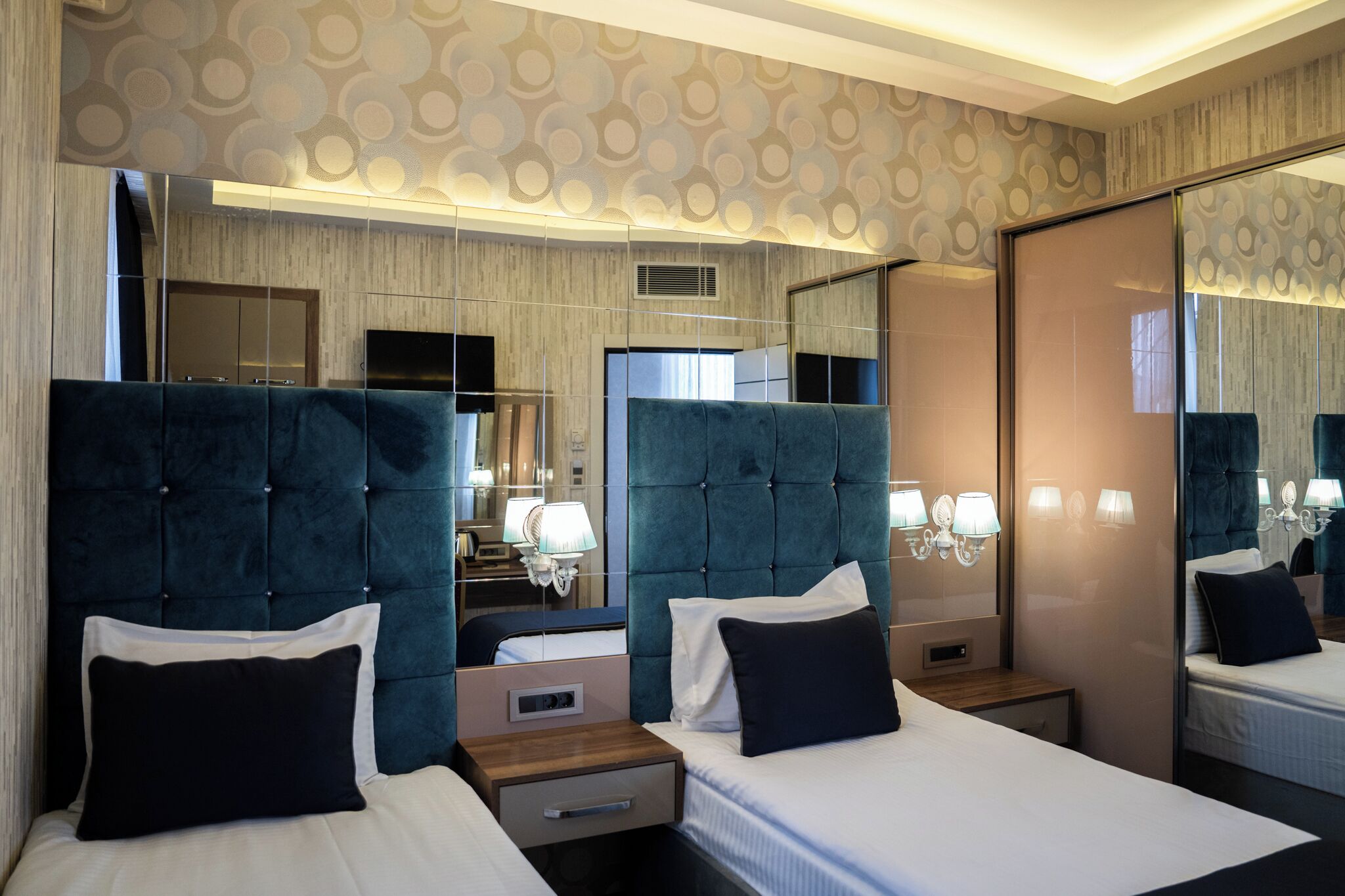 A hotel room with two beds, a large mirror, and a modern design.