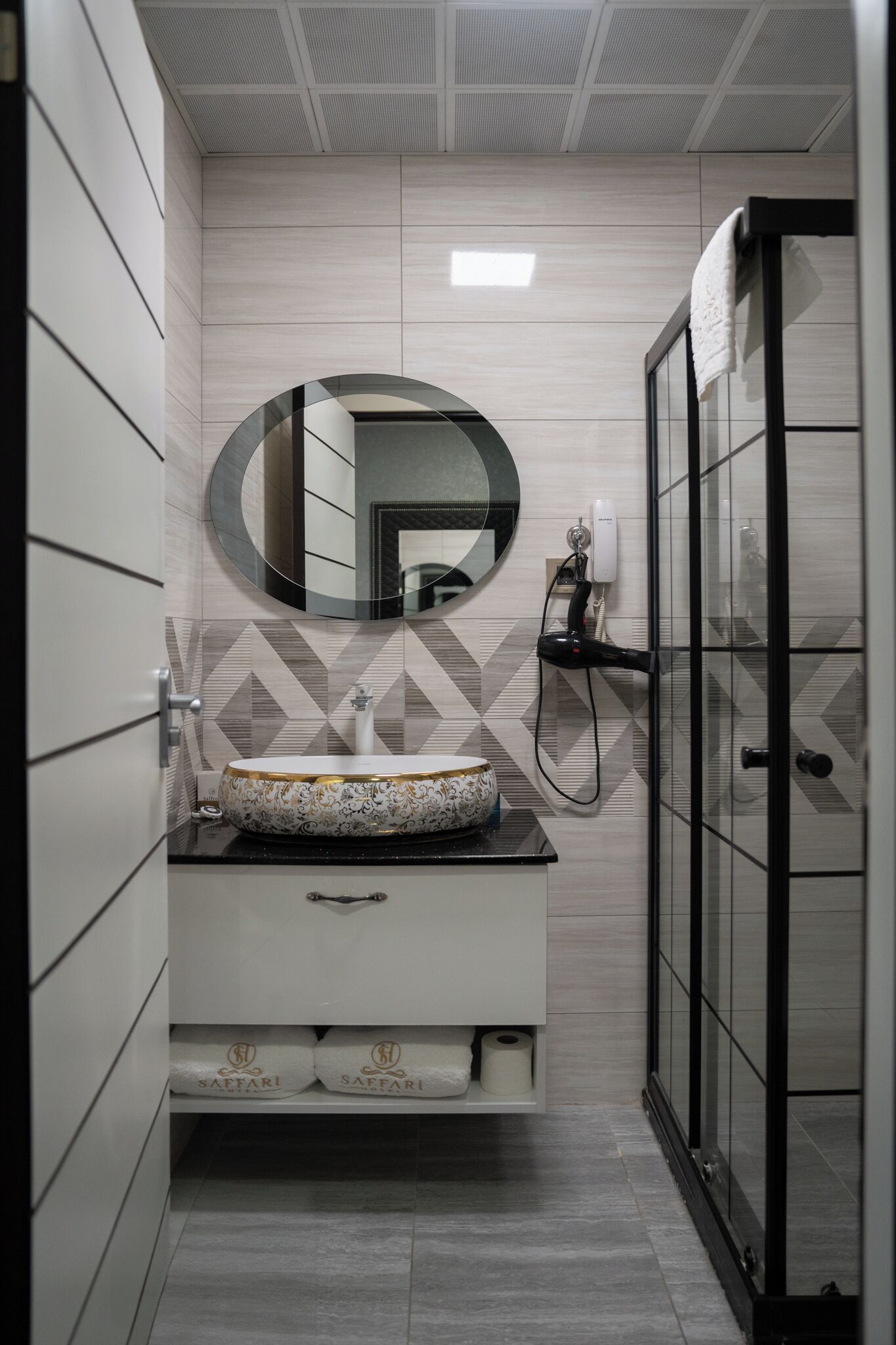 A bathroom with a round mirror, a sink with a decorative bowl, and a shower enclosure.