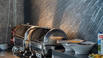 Buffet ben organitzat amb diverses estacions de menjar i una paret moderna i amb relleu al fons.