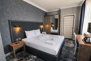 Une chambre d’hôtel avec un grand lit, une table de chevet, un miroir, un bureau et une bouilloire.