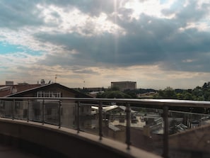 A view from a balcony with a railing, overlooking a cityscape with buildings and a partly cloudy sky. - Saffari Hotel (Ankara)