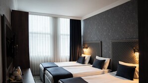 Habitación de hotel con dos camas, un escritorio y una televisión.