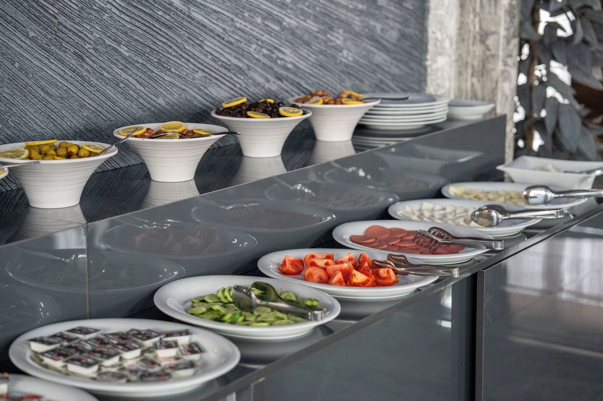 A buffet with various dishes including fruits, vegetables, and meats.