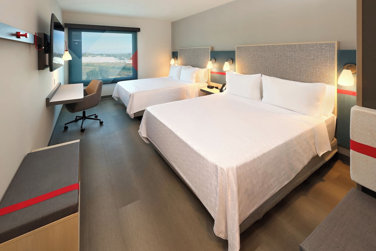Ein Hotelzimmer mit zwei Betten, einem Schreibtisch, einem Stuhl und einem Fernseher.