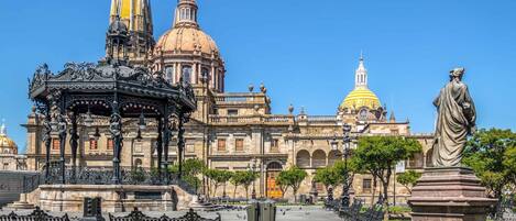 A historic building with ornate architecture, including a large dome and a statue in front.