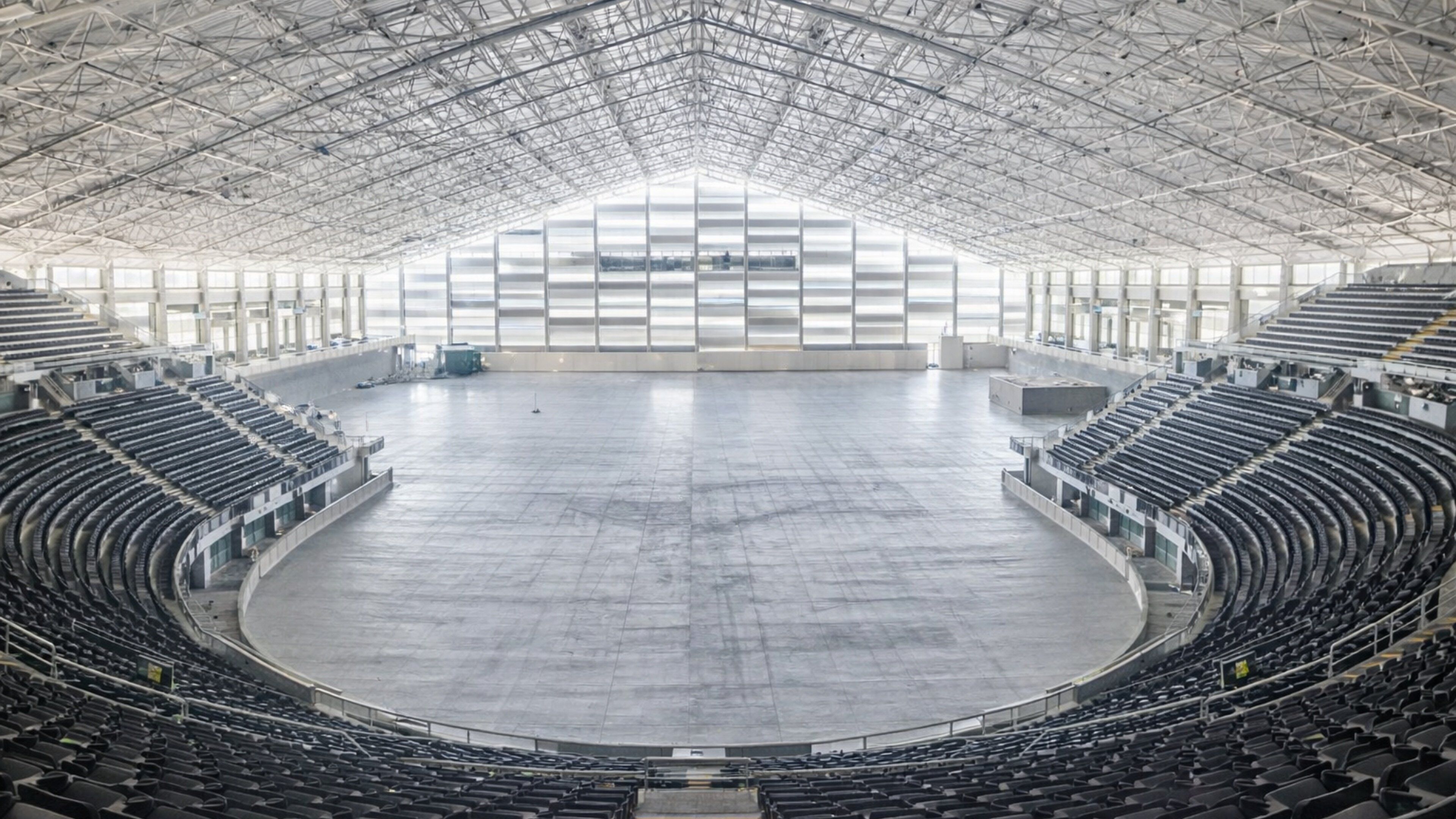 A large, empty indoor stadium with a high ceiling and a central open area.
