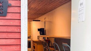 A compact kitchen with a microwave, coffee maker, and a small refrigerator. There are metal chairs and a wooden table.