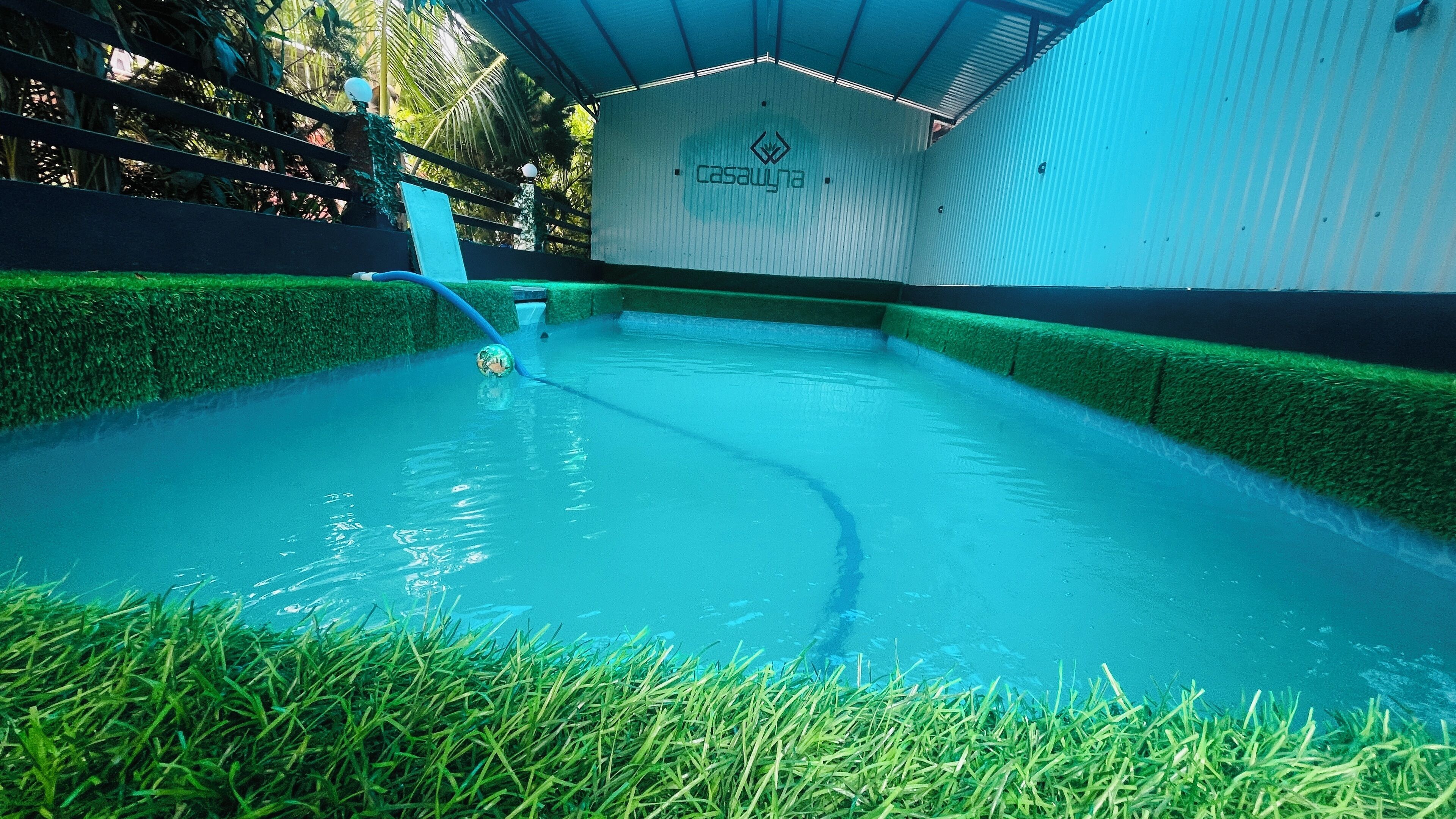 Una piscina con bordes de césped artificial y un letrero que dice Casawyna.