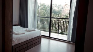 A bedroom with a large window, a bed, and a view of greenery outside. - Casa Wyna family Ayur center (Mananthavady)