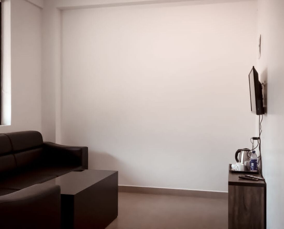 Un salon moderne avec un canapé marron foncé, une petite table basse et un téléviseur à écran plat fixé au mur.