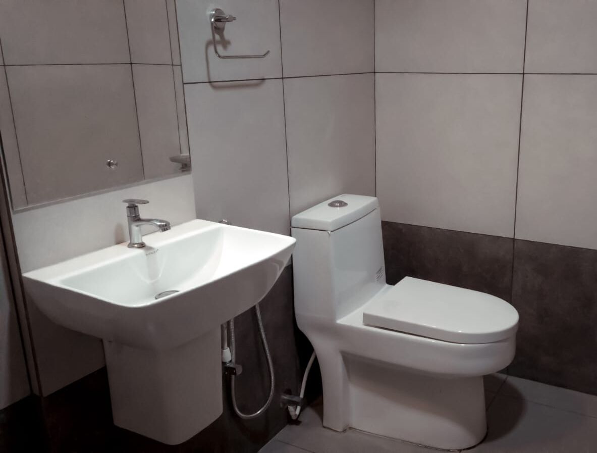 A bathroom with a white sink, toilet, and a towel rack on the wall.