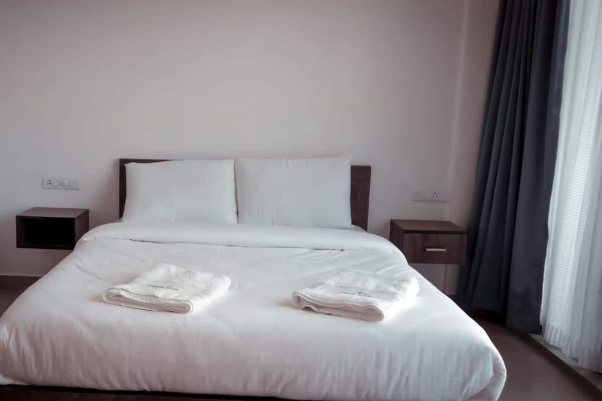 A neatly made bed with white linens and two folded towels on the bed.