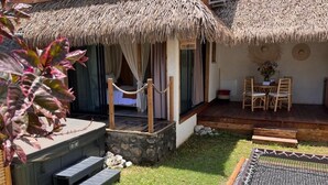 A cozy outdoor seating area with a thatched-roof structure, a small table with chairs, and a grill. - Les Vavangues 2 (Saint-Paul)