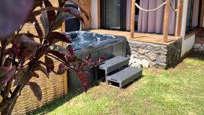 A hot tub with steps leading up to it, surrounded by a stone wall and a thatched-roof structure. - Les Vavangues 2 (Saint-Paul)