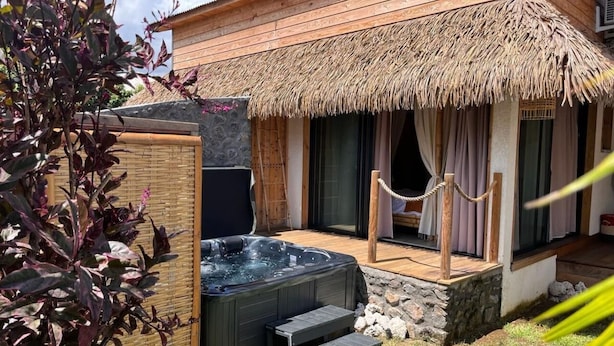 A spa area with a hot tub, wooden deck, and a thatched roof structure. - Les Vavangues 2 (Saint-Paul)