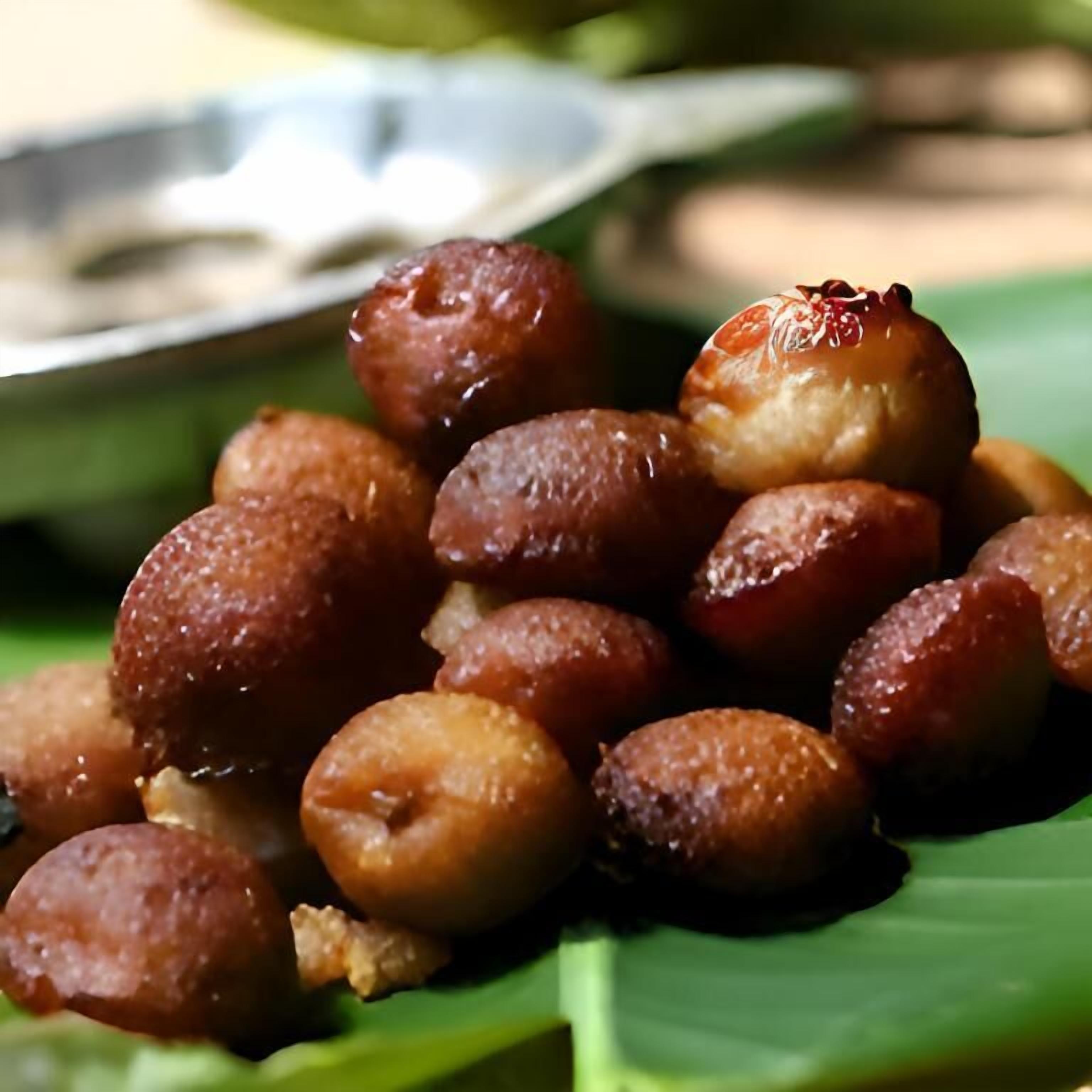 A plate of round, golden-brown sweets on a green leaf.