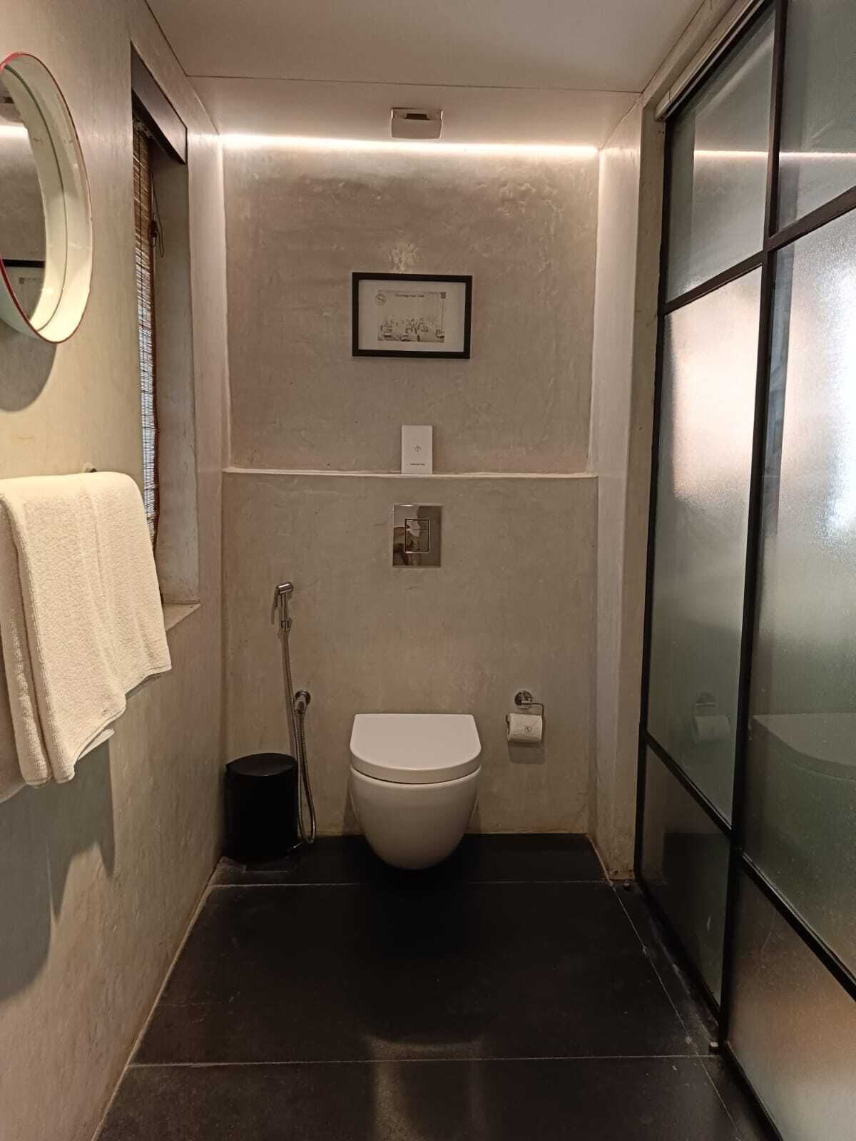 A compact bathroom with a toilet, a hand dryer, and a towel hanging on the wall.