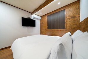 Un dormitorio con cama, televisor montado y armario.